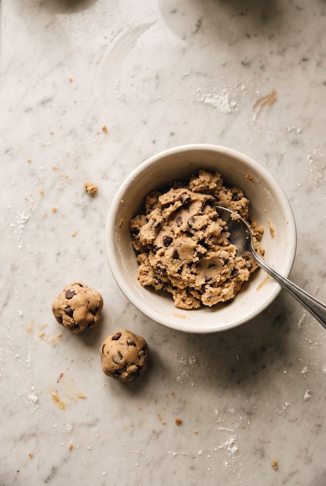 A small bowl of edible cookie dough with a spoon and mini chocolate chips