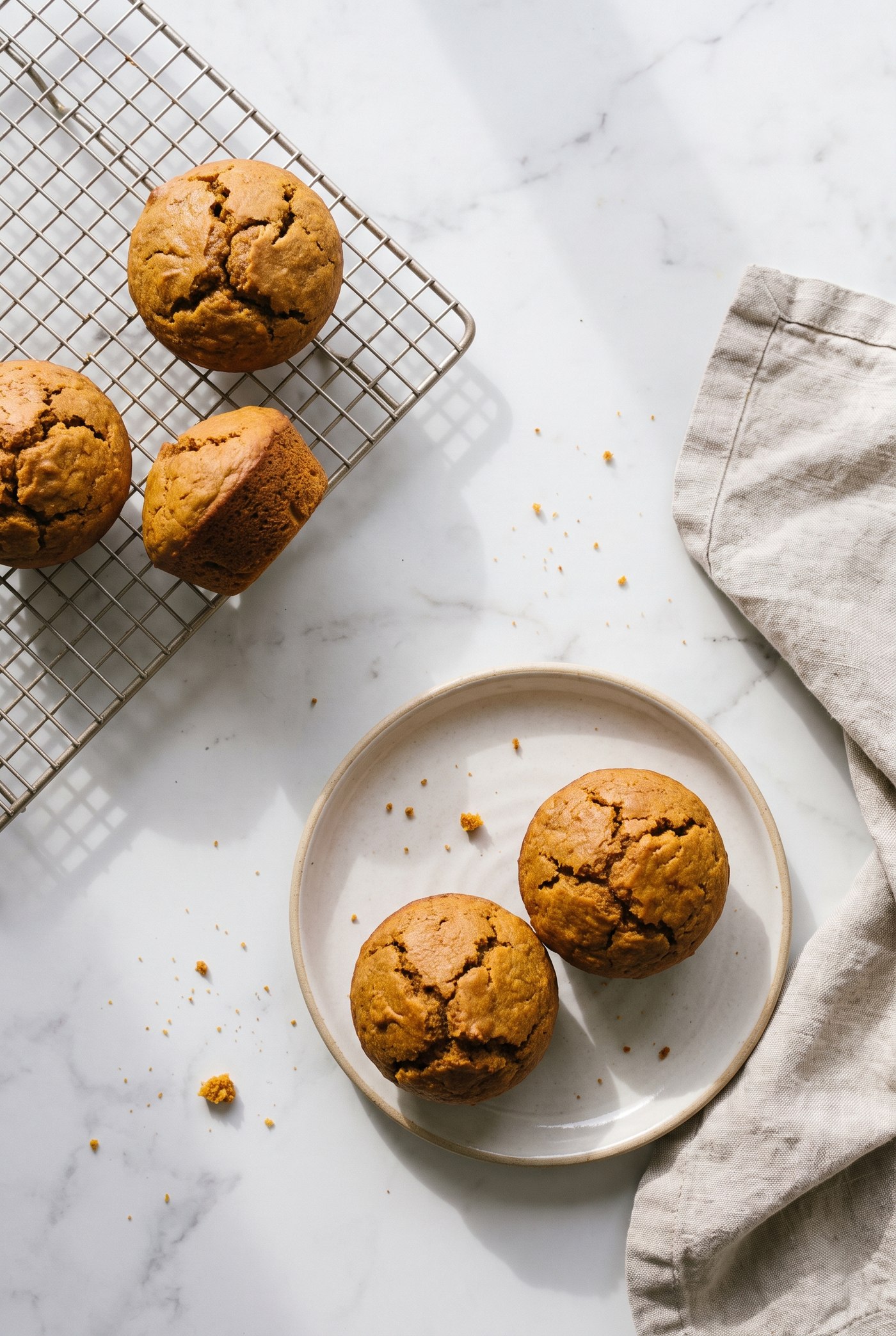 Pumpkin protein muffins on a cooling rack with one split open